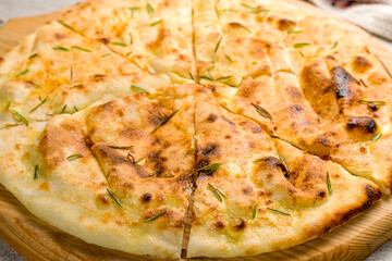 Focaccia with rosemary on the board on grey concrete table macro close up