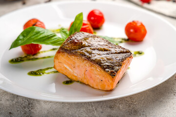 Salmon steak on the grill on white plate on grey concrete table macro close up