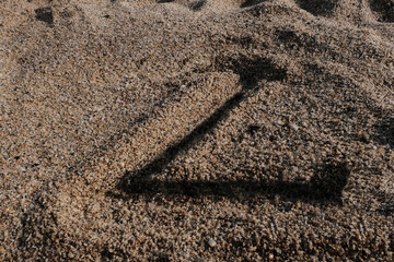English alphabet. Sand on the beach. The letter L