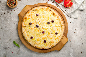 Pizza Quattro formaggi on wooden board with grapes on grey concrete table top view
