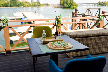 Pizza with arugula and shrimp on table near a water