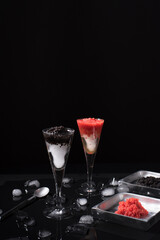 Caviar de esturión negro y caviar de salmón rojo servido en copa de cóctel helada sobre fondo negro	