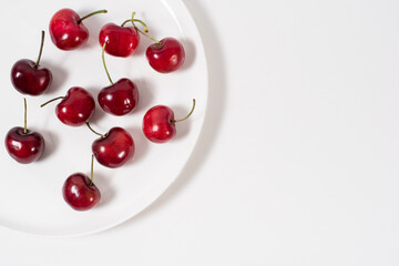 Cerezas dulces fruta en un plato blanco y fondo blanco. Vista superior	