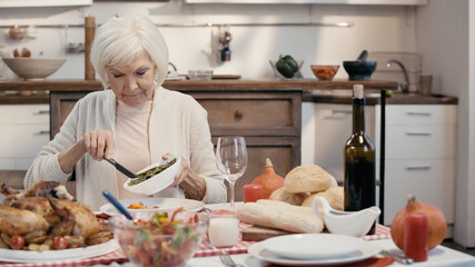 senior woman with grey hair having thanksgiving dinner in kitchen.