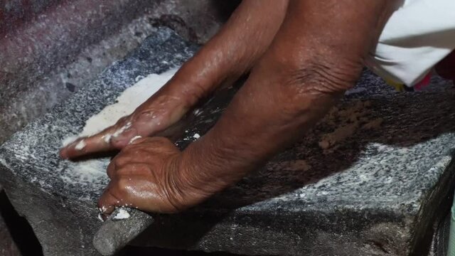 Woman hands grinding corn into metate 