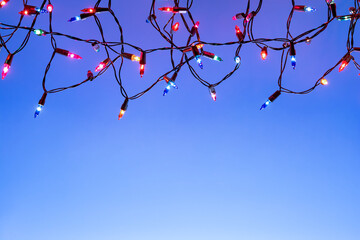 Christmas lights string on blue background with copy space..