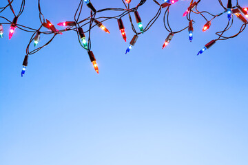 Christmas lights string on blue background with copy space..