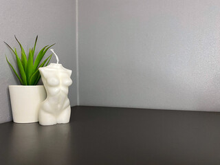 Beautiful female body shaped candle on gray table. Stylish decor