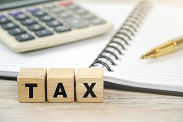 Tax concept with wooden blocks desk background with calculator, notebook, pen on business background.                             