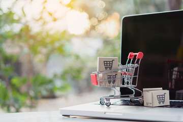 Shopping online. Cardboard box with a shopping cart logo in a trolley on laptop keyboard. Shopping...