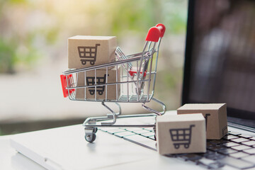 Shopping online. Cardboard box with a shopping cart logo in a trolley on laptop keyboard. Shopping...