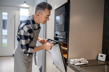 Man sideways to camera looking into open oven