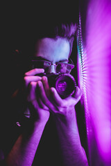 Male photographer at a party with neon lights.