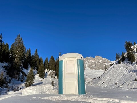 Portable chemical toilet in idyllic snow-covered winter landscape. 