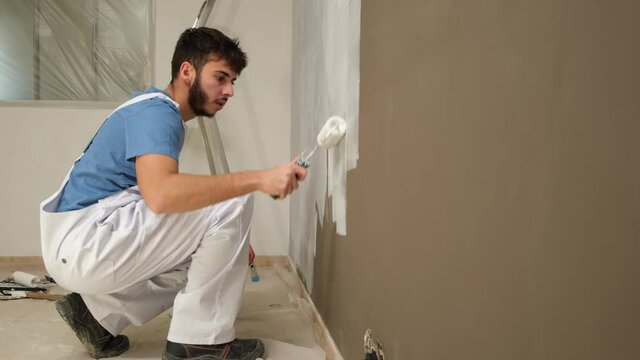 handsome young man professional painter in construction site wall painting renovation in a client house
