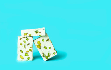 Nougat with pistachios on blue background.Turkish delight or Arabic dessert. Creative copy space