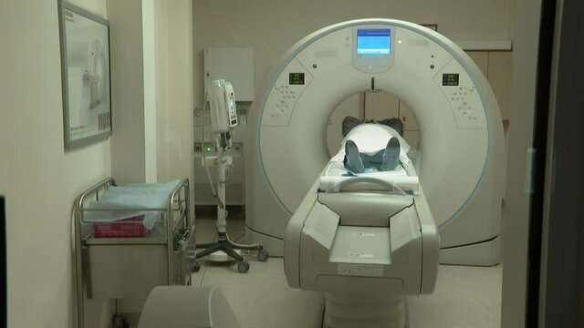 In Medical Laboratory Patient Undergoes MRI or CT Scan Process under Supervision of Radiologist, in Control Room Doctor Watches Procedure in Monitors