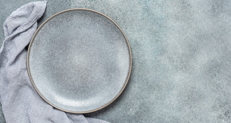 Empty gray plate and gray napkin on gray rustic concrete background. Top view, flat lay. Banner