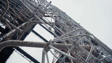 bottom view of old radio tower in chernobyl zone against grey sky.