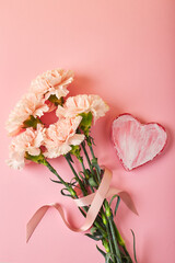 Bouquet of pink carnations. Design concept of holiday greeting with carnation bouquet on pink table background