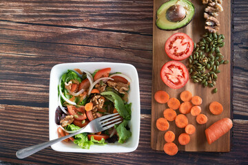 Fototapeta na wymiar Vegetable salad plate on vintage wooden background. Healthy vegetarian food, top view.