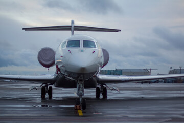 A twin-engine business jet plane stands at the airport in the parking lot at summer 