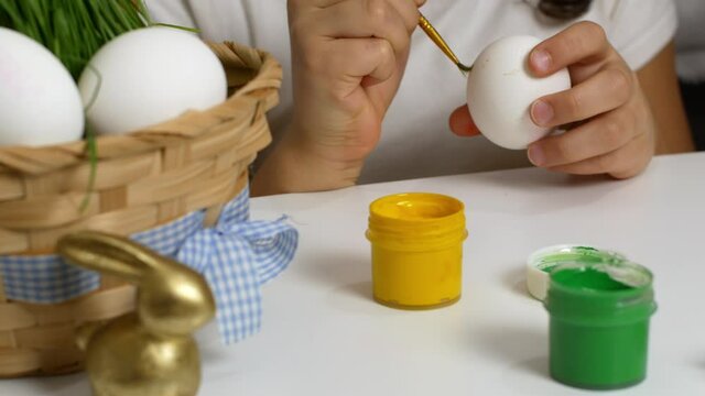 Happy Easter. Children drawing on painted eggs at the table, at home. Preparing for the Easter holiday.
