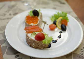 Macro shot, bread and butter with red caviar and olives on a plate, a sandwich