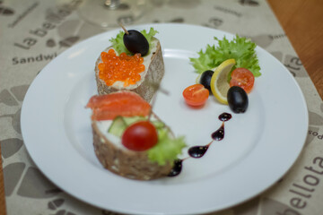 Macro shot, bread and butter with red caviar and olives on a plate, a sandwich