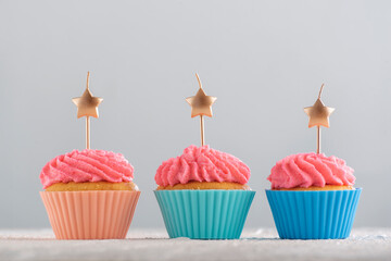 Golden candles in the shape of star on cupcakes with pink buttercream frosting. Birthday cupcakes. Party food. Close up