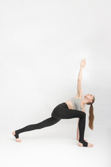 Triangle Pose. Trikonasana. Sports girl does yoga and performs asanas on white background. Gymnastics, stretching. Vertical frame