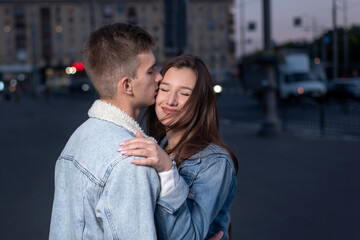 Young couple in love hugs on evening city background