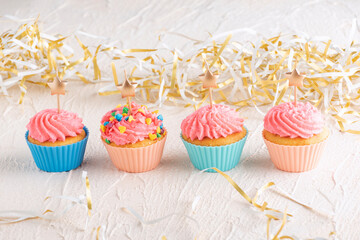 Muffins with pink buttercream frosting with candle in the shape of star. Delicious party food.