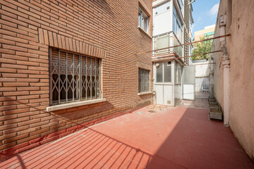 Patio on the ground floor of a building with a clay brick facade and aluminum balconies