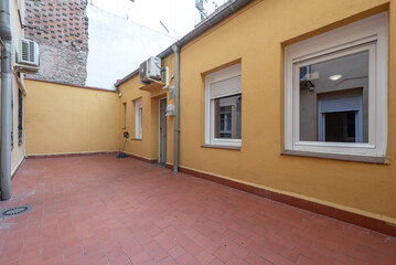 Ground floor house with several windows and patio with clay floors