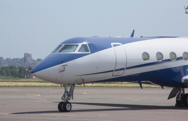 A twin-engine business jet plane stands at the airport in the parking lot at summer 