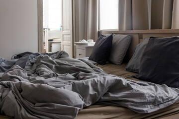 An unmade bed with two duvets in gray duvet covers. Morning concept