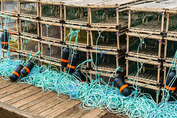 Lobster traps, buoys and lots of rope piled up on a wharf.