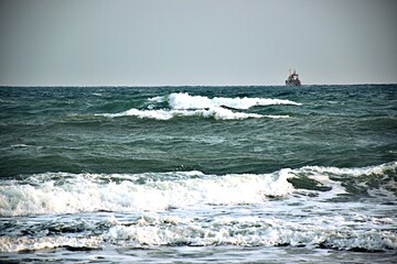 On the horizon, a trawler sails along the sea waves
