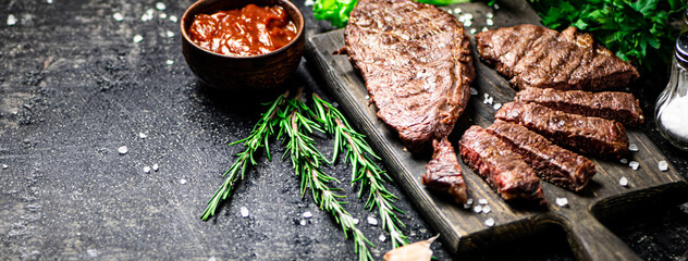 Fototapeta Steak grill on a cutting board with rosemary. Against a dark background. High quality photo obraz