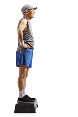 Full length profile shot of an elderly man standing on a step aerobic platform