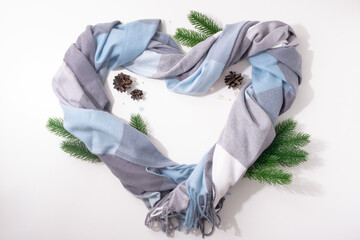 Heart is made of cashmere scarf with fir branches and cones
