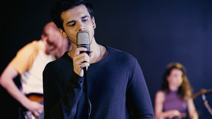 young man singing song with blurred music band.