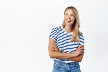 Fototapeta premium Beautiful happy girl laughing and smiling. Modern scandinavian woman posing against white background, looking happy, wearing summer clothes