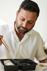Un hombre con una bandeja con piezas variadas de sushi. Rollo California.
