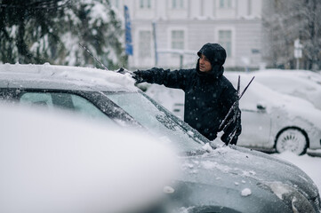 Middle aged man cleaning car from snow and ice