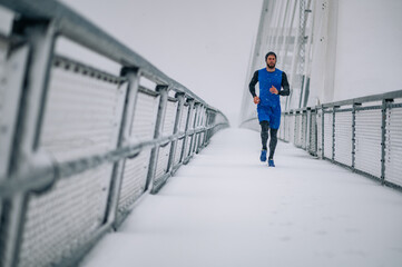 Man running on bridge during a winter snow day.