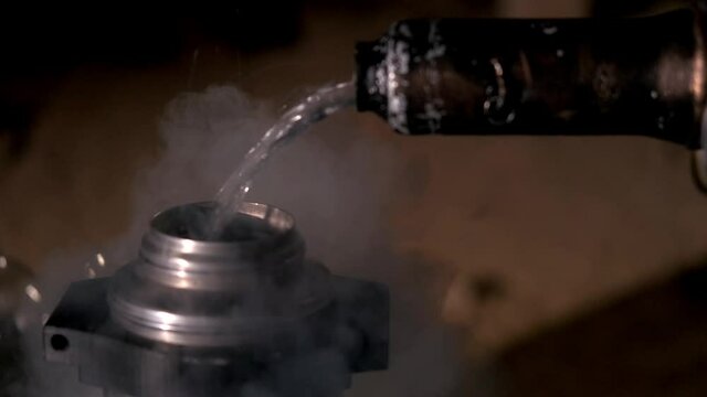 Masculine hands pour liquid nitrogen from the dewar vessel into a thermos. Steam is spreading around. The concept of alchemy. Steampunk
