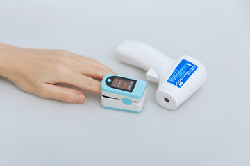 Pulse oximeter and thermometer gun on white background. Infrared isometric thermometer gun to check body temperature for virus symptoms. Measuring oxygen saturation, pulse rate and oxygen levels.