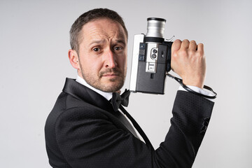A parody of James Bond, a man wearing a tuxedo  handling a Super 8 camera in a classic 007 pose.